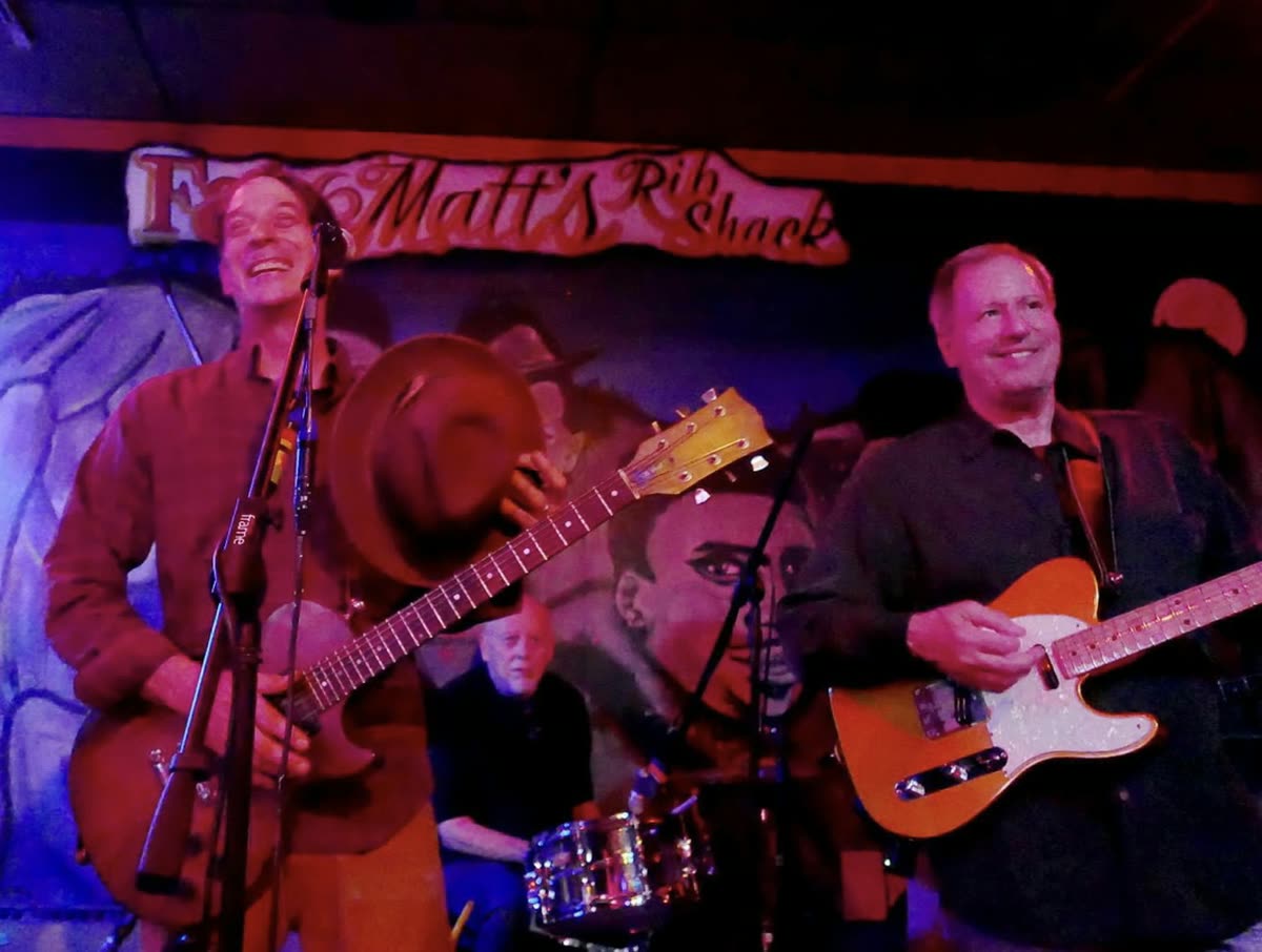 Joe Caporaso playing guitar on stage with a band